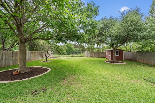 view of yard featuring an outbuilding, a fenced backyard, and a storage shed