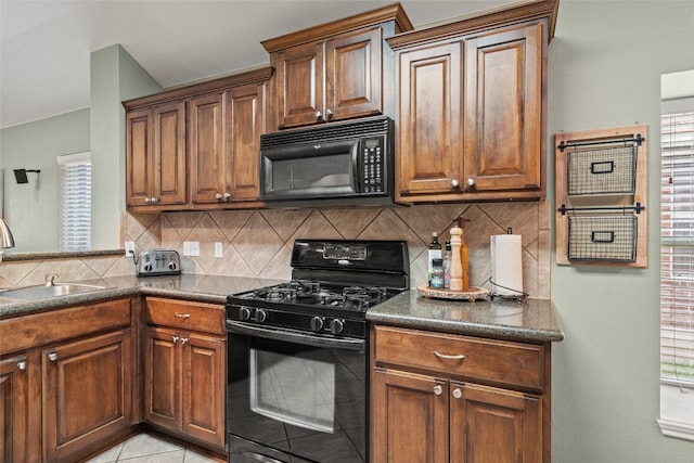 kitchen with dark countertops, a sink, black appliances, and tasteful backsplash