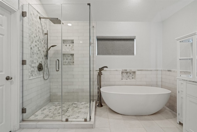full bathroom featuring vanity, a freestanding tub, wainscoting, tile walls, and a shower stall