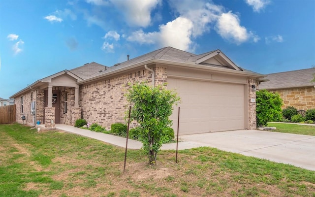 view of side of property featuring driveway, a garage, brick siding, fence, and a yard
