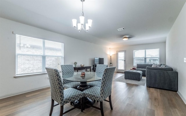 dining area with baseboards, a notable chandelier, wood finished floors, and visible vents