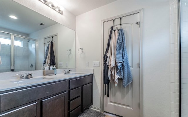 full bathroom with a sink, a stall shower, double vanity, and visible vents