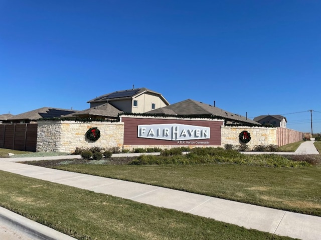 community / neighborhood sign featuring fence and a yard
