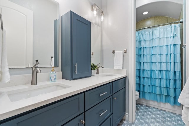 full bathroom featuring double vanity, a sink, a shower with shower curtain, and toilet