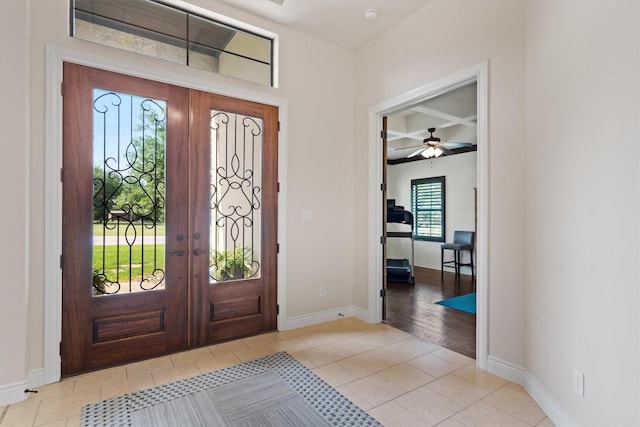 tiled entryway featuring beam ceiling, french doors, a ceiling fan, baseboards, and coffered ceiling