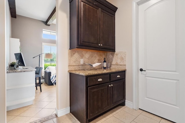 bar featuring baseboards, light tile patterned floors, backsplash, and beam ceiling