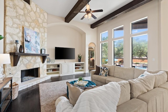living area with arched walkways, beamed ceiling, plenty of natural light, and a ceiling fan
