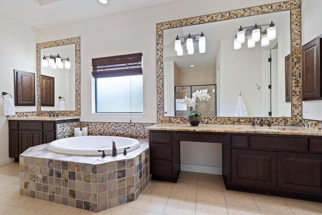 bathroom featuring tile patterned floors, a bath, two vanities, a shower stall, and backsplash