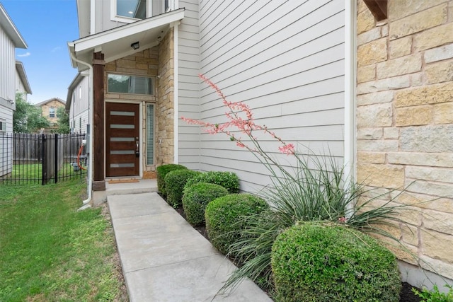 property entrance featuring fence and stone siding