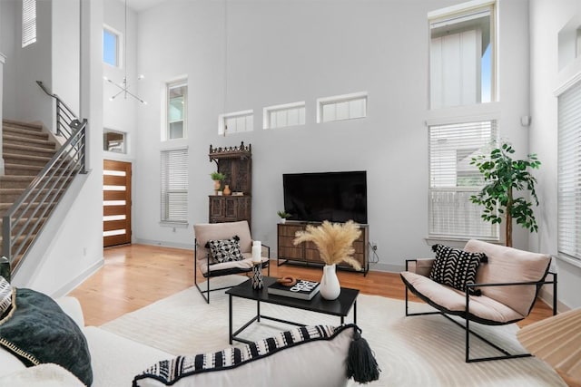 living area with wood finished floors, baseboards, stairs, and a high ceiling