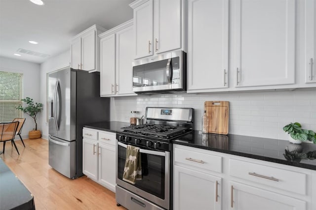 kitchen featuring white cabinets, appliances with stainless steel finishes, light wood-style flooring, and tasteful backsplash