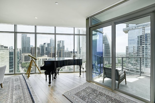 interior space with a city view, floor to ceiling windows, wood finished floors, and a wealth of natural light