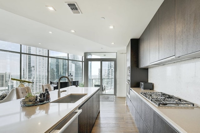 kitchen with appliances with stainless steel finishes, a sink, light wood finished floors, light countertops, and modern cabinets