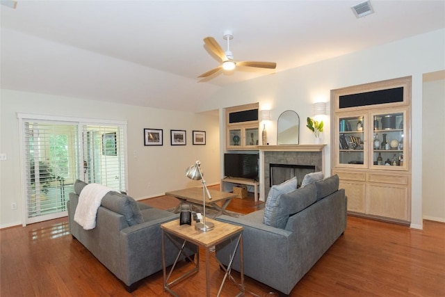 living area featuring a fireplace, a ceiling fan, baseboards, wood finished floors, and visible vents
