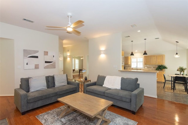 living room featuring ceiling fan, visible vents, wood finished floors, and vaulted ceiling
