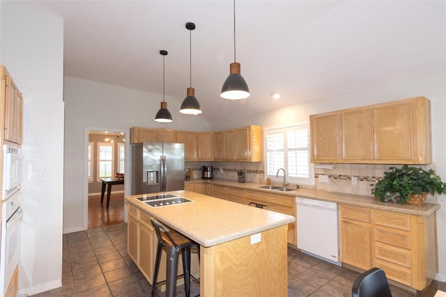 kitchen with light brown cabinetry, a sink, white appliances, decorative backsplash, and a kitchen island