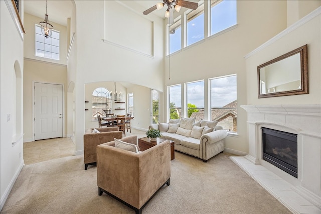 living room featuring a healthy amount of sunlight, arched walkways, light carpet, and a towering ceiling