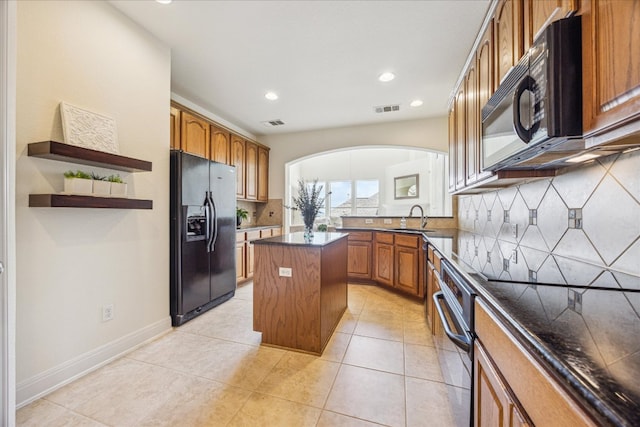 kitchen featuring brown cabinets, decorative backsplash, a sink, and black appliances