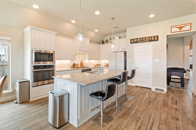 3105 High Meadow St, Seguin, TX 78155 - kitchen featuring appliances with stainless steel finishes, a sink, backsplash, light wood-type flooring, and white cabinetry