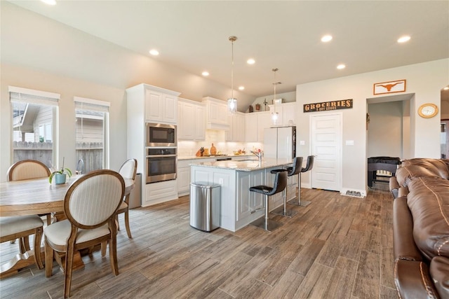 3105 High Meadow St, Seguin, TX 78155 - kitchen featuring appliances with stainless steel finishes, open floor plan, white cabinetry, a breakfast bar, and light wood-style floors