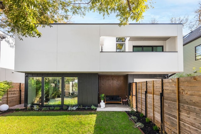 rear view of property featuring a lawn, a fenced backyard, and a patio area