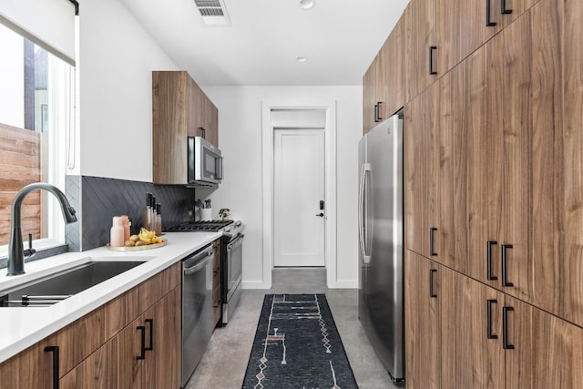 kitchen with brown cabinetry, visible vents, modern cabinets, a sink, and stainless steel appliances