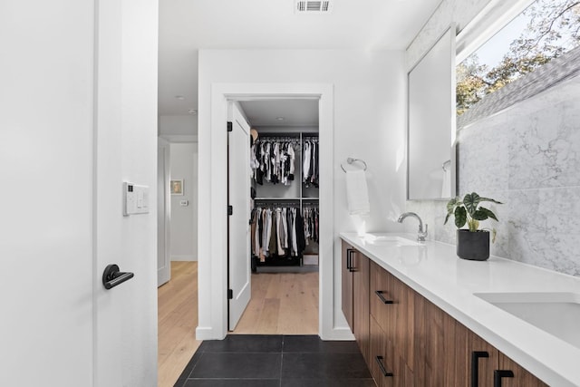full bath featuring double vanity, a sink, a walk in closet, and tile patterned floors