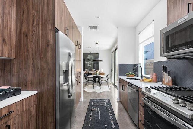 kitchen with a sink, appliances with stainless steel finishes, modern cabinets, and finished concrete floors