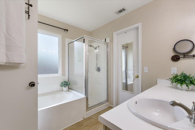 bathroom featuring visible vents, wood finished floors, a bath, and a shower stall