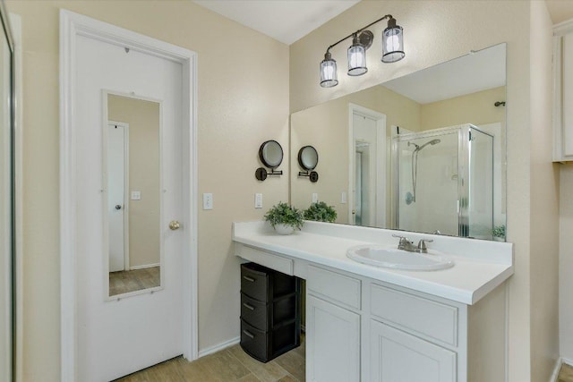 bathroom featuring vanity, baseboards, a stall shower, and wood finished floors