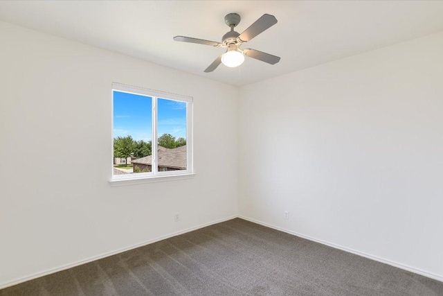spare room featuring baseboards, a ceiling fan, and dark carpet
