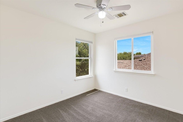 spare room featuring ceiling fan, visible vents, baseboards, and dark carpet