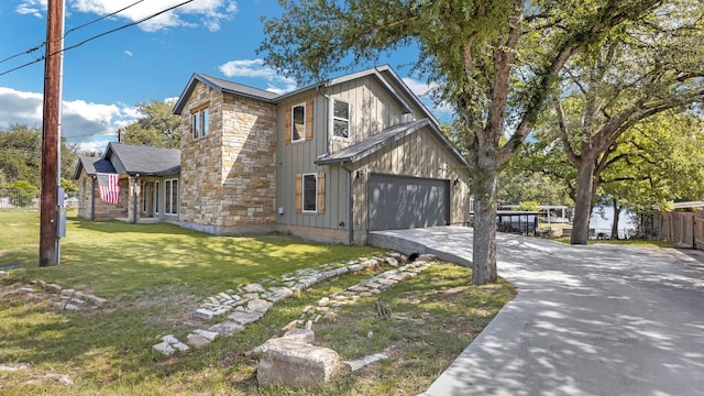 view of property exterior featuring fence, stone siding, a garage, a lawn, and driveway
