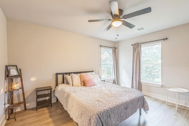 bedroom featuring light wood-type flooring, a ceiling fan, baseboards, and visible vents