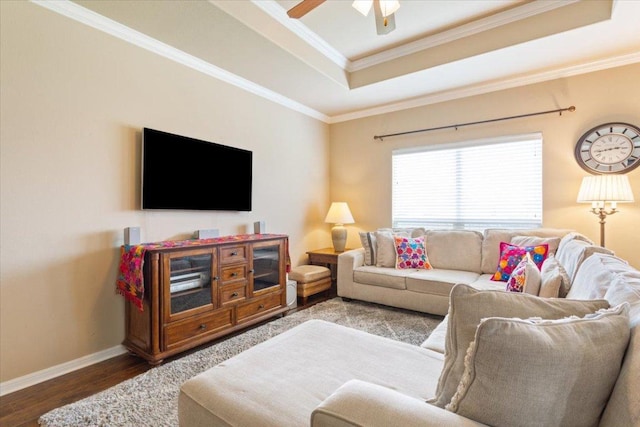 living area with ceiling fan, a raised ceiling, baseboards, wood finished floors, and ornamental molding