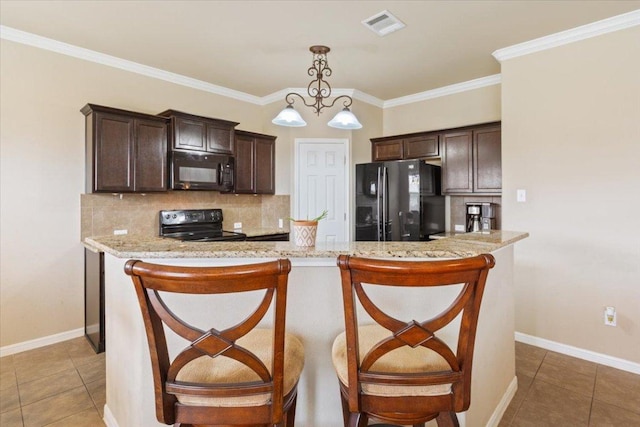 kitchen featuring tasteful backsplash, dark brown cabinetry, black appliances, and visible vents