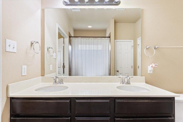 bathroom featuring a sink, curtained shower, and double vanity