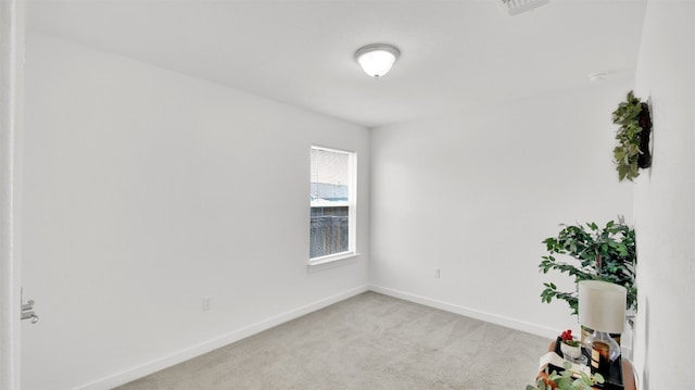 empty room featuring baseboards, visible vents, and light colored carpet