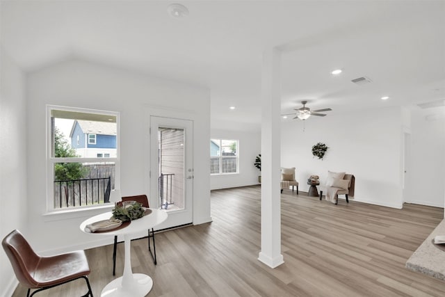 interior space with a ceiling fan, vaulted ceiling, visible vents, and light wood finished floors