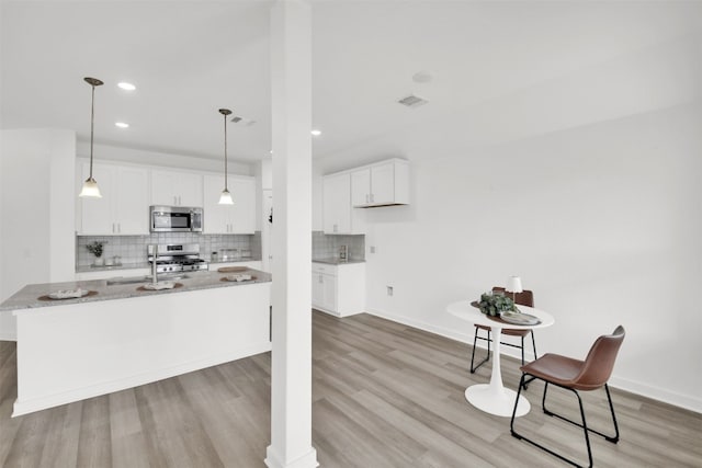 kitchen with white cabinetry, appliances with stainless steel finishes, tasteful backsplash, and light wood-style floors