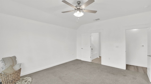 unfurnished bedroom featuring ceiling fan, carpet, baseboards, lofted ceiling, and visible vents