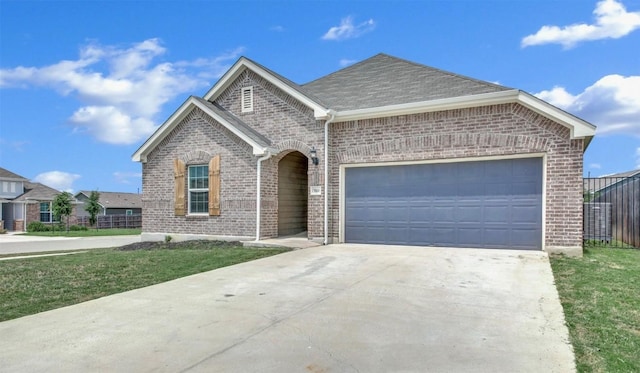 view of front facade with fence, roof with shingles, brick siding, a garage, and driveway