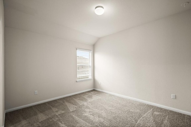 carpeted empty room with baseboards and lofted ceiling