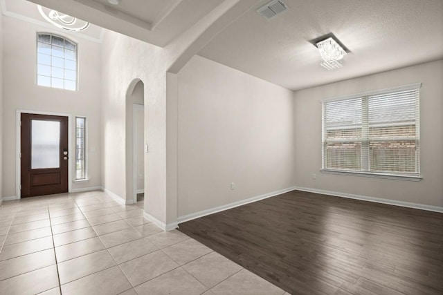 foyer featuring arched walkways, baseboards, visible vents, and light tile patterned flooring