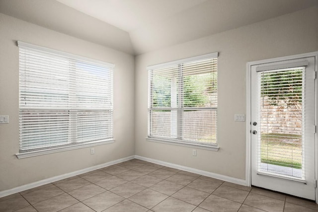 unfurnished room featuring light tile patterned floors, baseboards, and vaulted ceiling