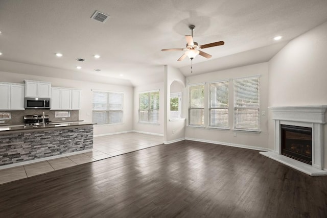 unfurnished living room with visible vents, a glass covered fireplace, recessed lighting, light wood-type flooring, and a ceiling fan