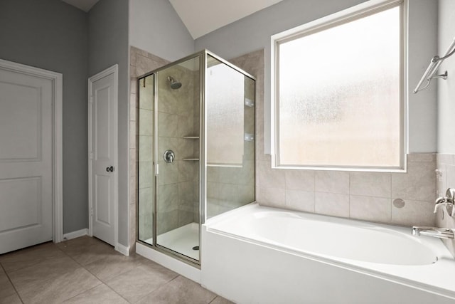 full bathroom featuring tile patterned flooring, a bath, vaulted ceiling, and a shower stall