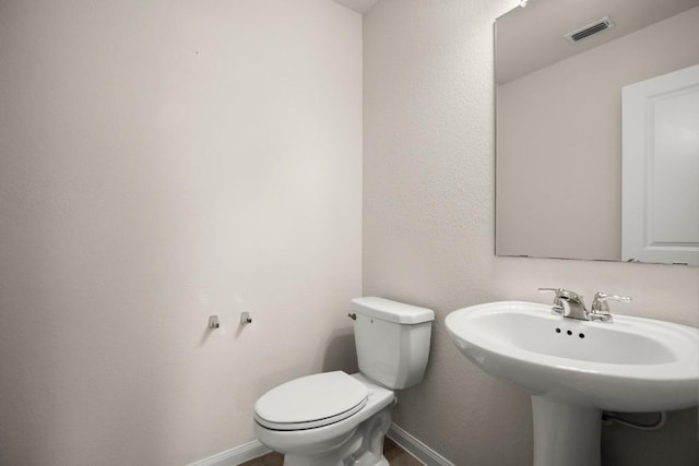 bathroom with a sink, baseboards, toilet, and visible vents