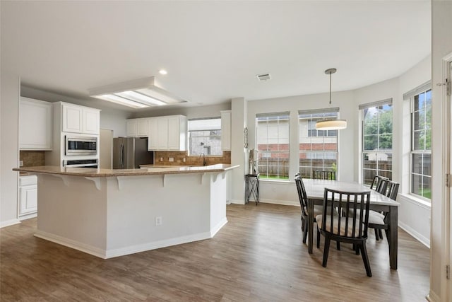 2045 Saint Andrews Dr, Round Rock, TX 78664 - kitchen featuring backsplash, wood finished floors, white cabinets, appliances with stainless steel finishes, and recessed lighting