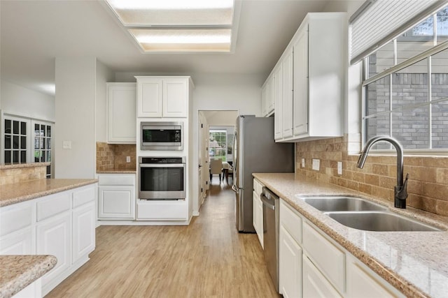 2045 Saint Andrews Dr, Round Rock, TX 78664 - kitchen with appliances with stainless steel finishes, backsplash, white cabinets, light wood-style flooring, and light stone countertops